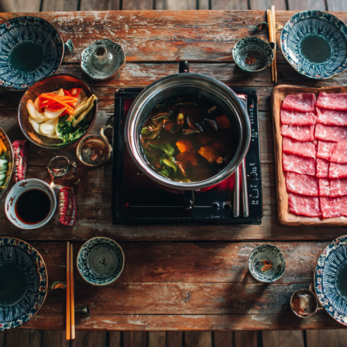 Complete shabu shabu dinner table setup with hot pot, ingredients, and dipping sauces