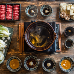 Shabu shabu recipe with beef, vegetables, and dipping sauces on a warm dinner table